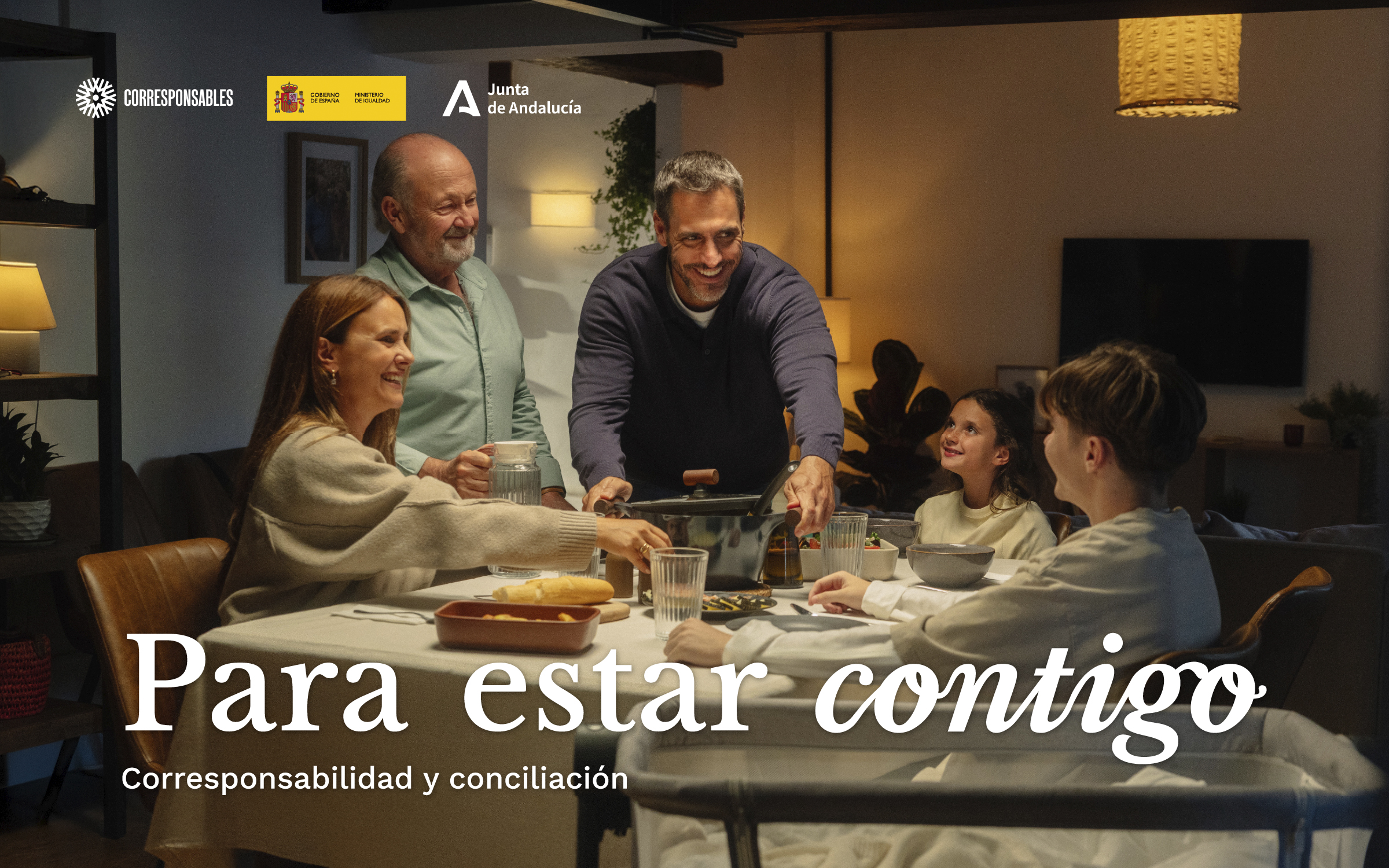 Una familia de varias generaciones comparte la cena mientras el padre sirve la mesa. Para estar contigo. Corresponsabilidad y conciliación.