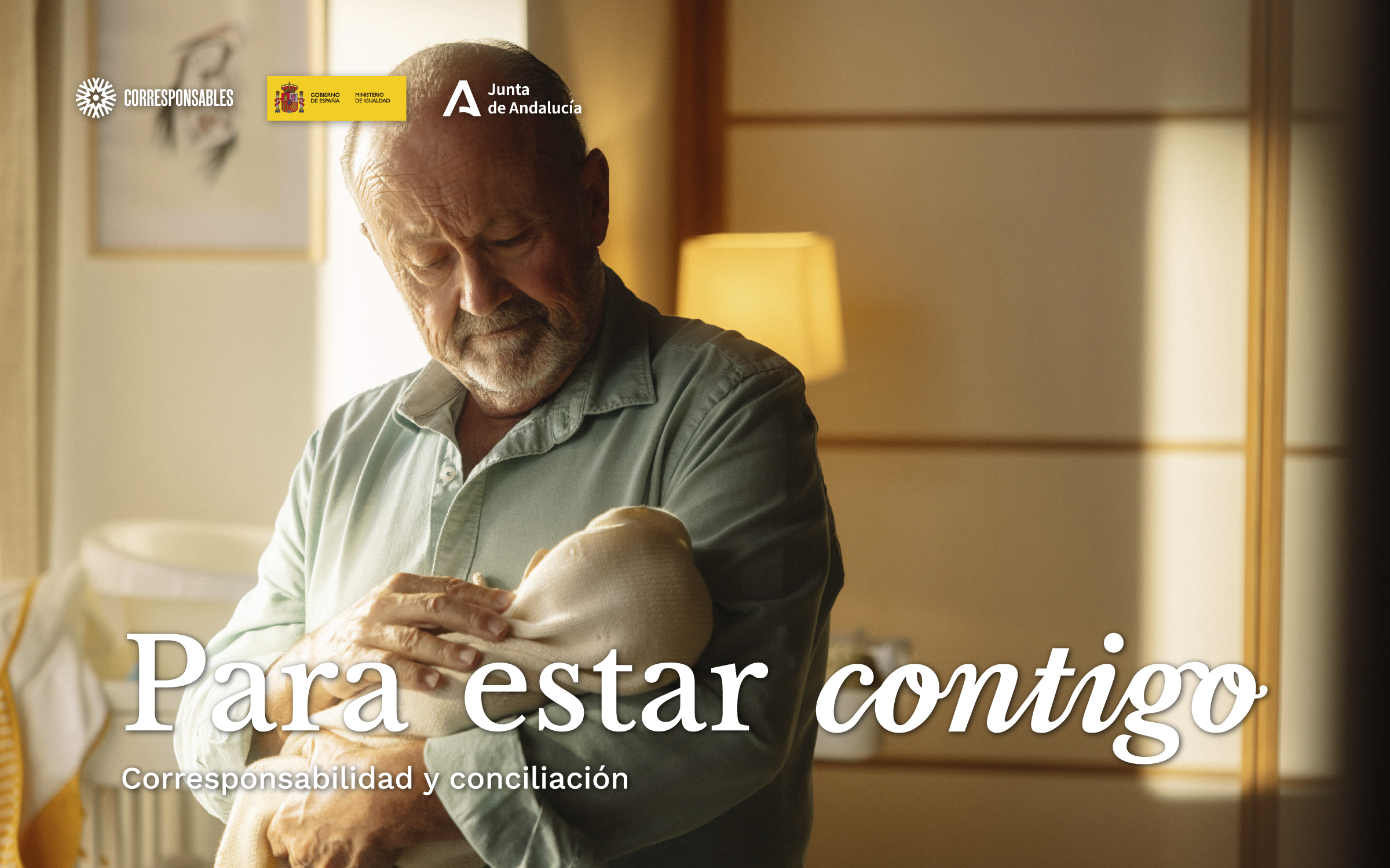 Un abuelo sostiene con ternura a un bebé en brazos. Para estar contigo. Corresponsabilidad y conciliación.
